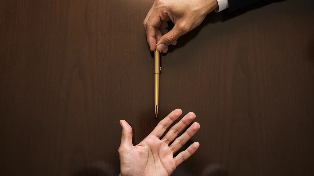 A symbolic overhead view of two hands reaching toward the same golden pen from opposite sides of a dark polished table, representing opposing interpretations in a contract negotiation.