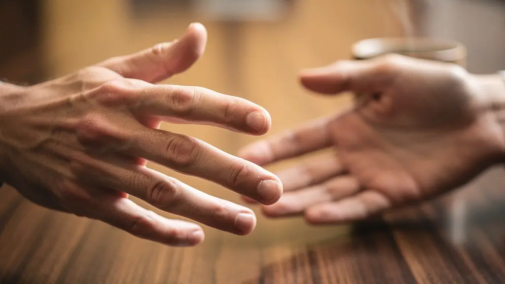 Close-up of a hand extending a warm gesture across a polished wooden conference table with soft natural light