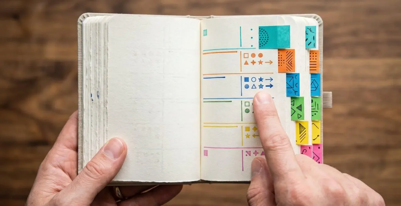Close-up of hands organizing structured meeting notes in a professional notebook with colored tabs